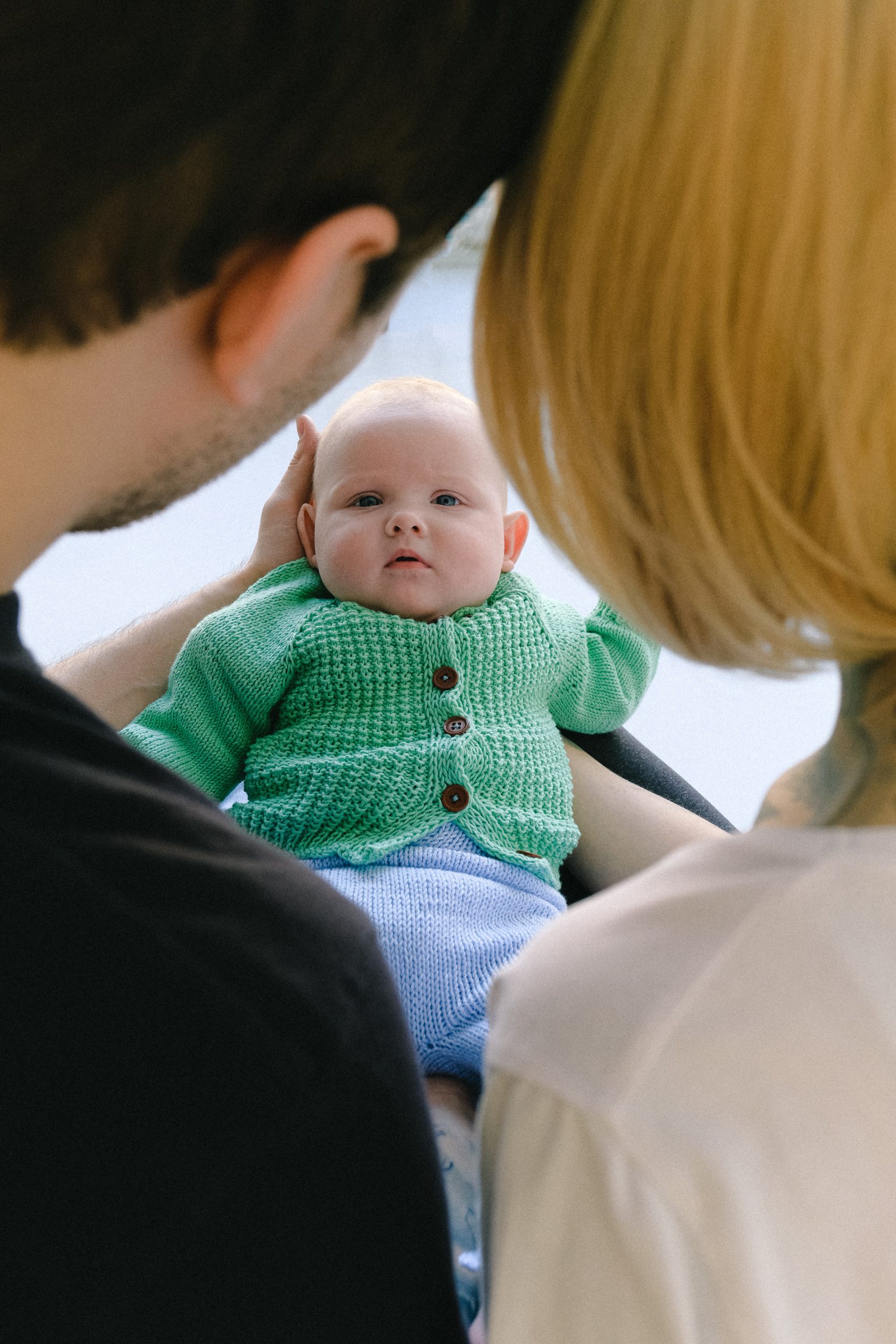 Un père et une mère portant leur bébé en le regardant.